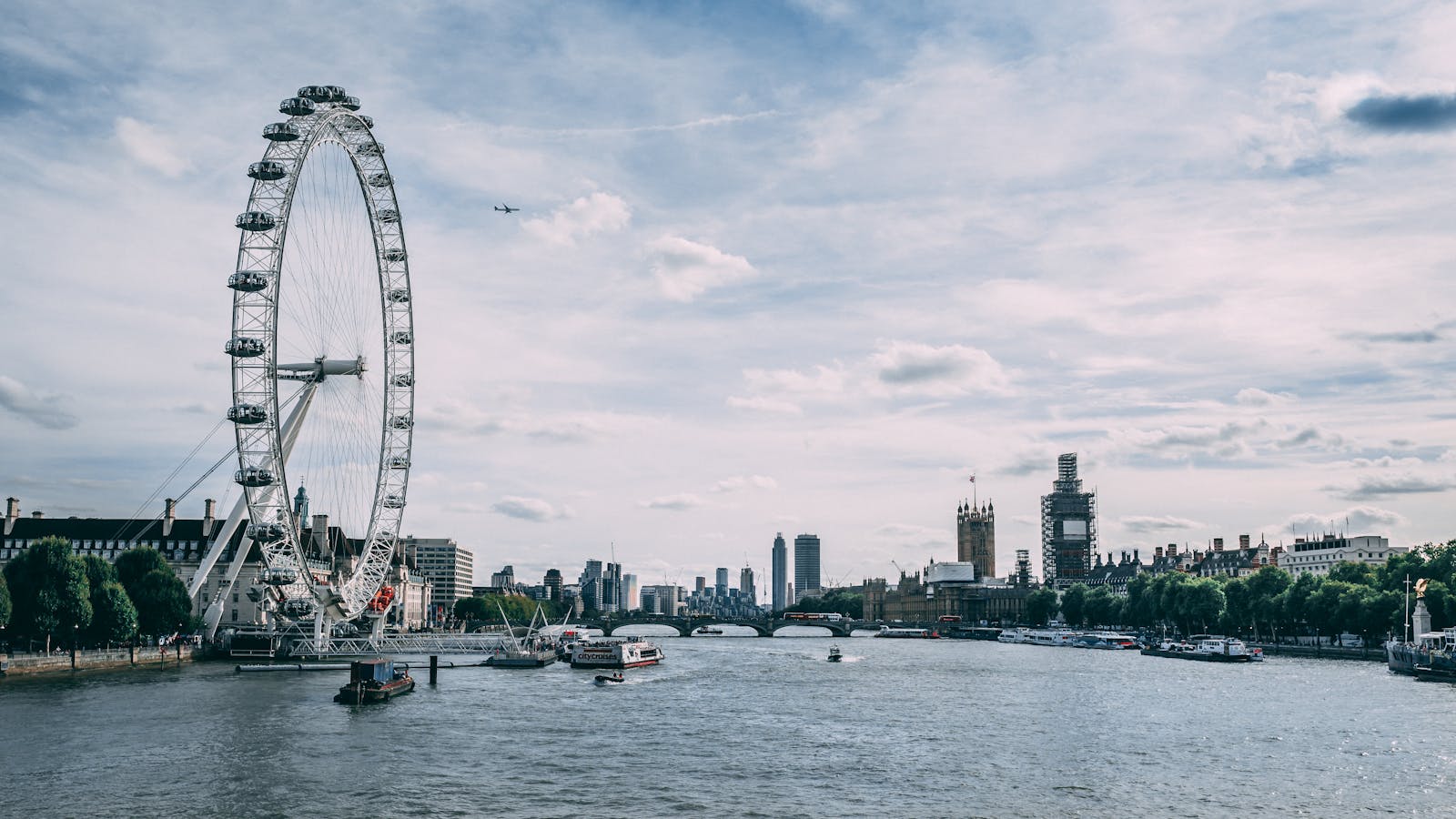 Scenic view of the London Eye on the River Thames with clear blue skies and city skyline.